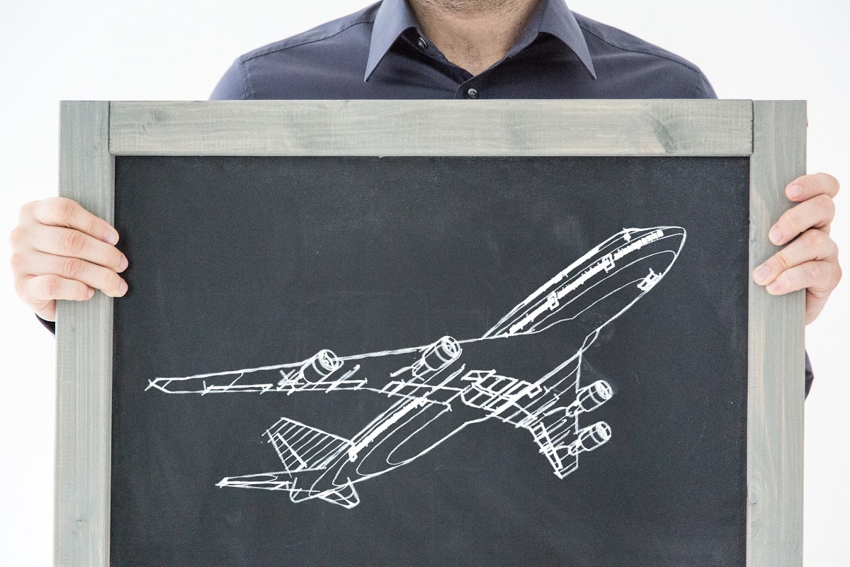 man holding chalkboard with airplane sketch