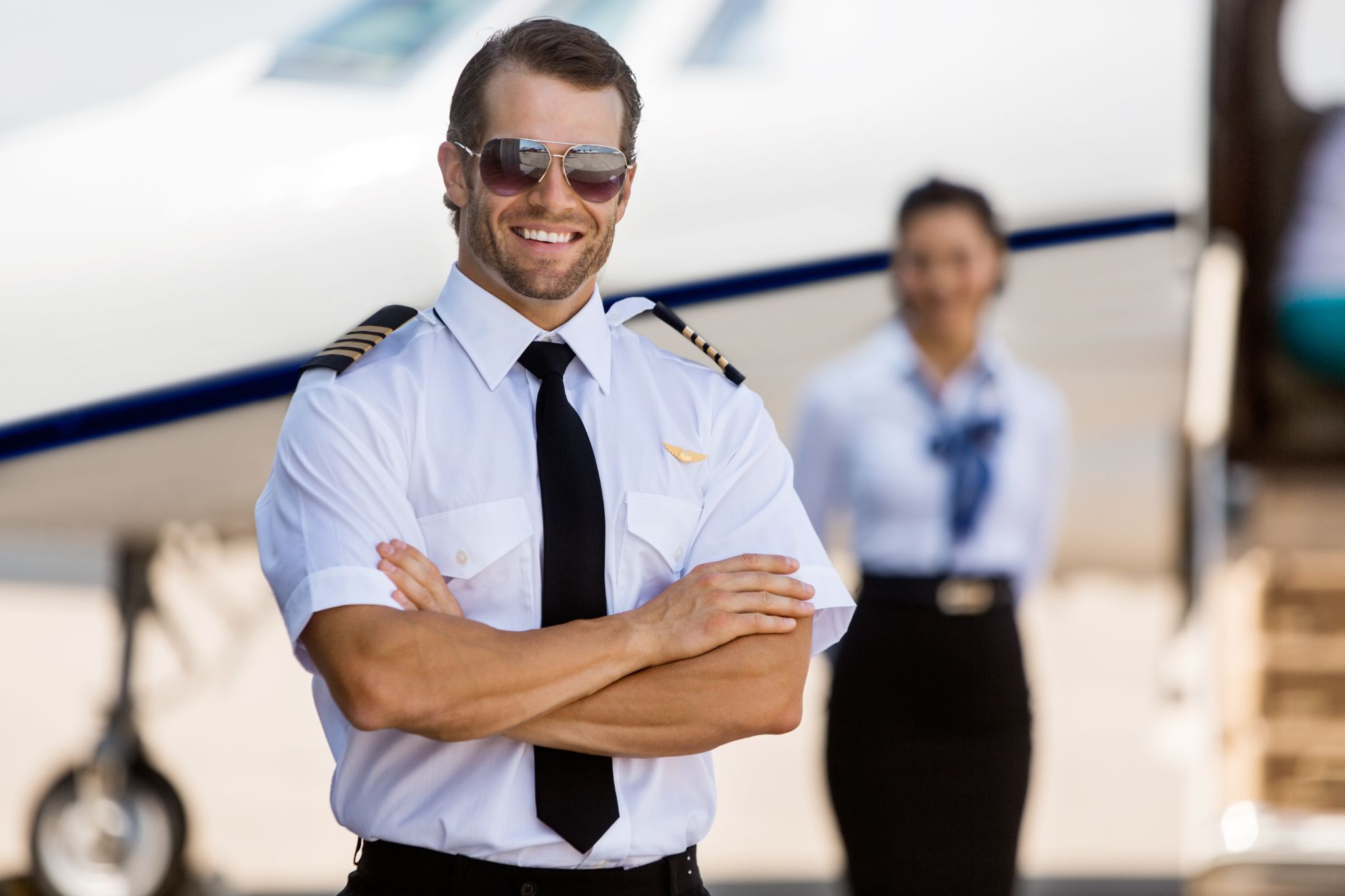 pilot hat and id holder with epaulets and sun glasses laying on log book and flight plan.