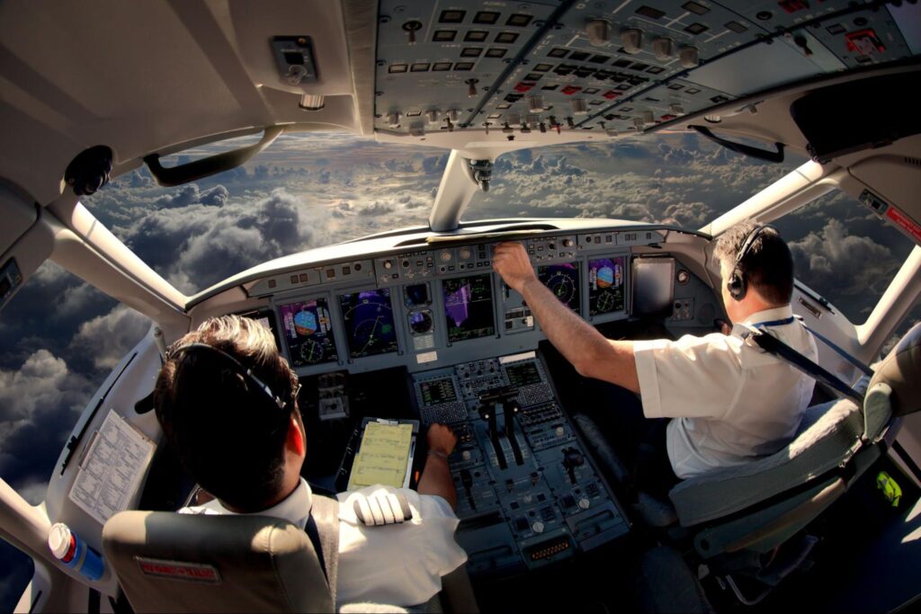 Flight Deck of modern passenger jet aircraft. Pilots at work. Cloudy sky and sunset view from the airplane cockpit.
