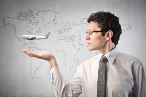 Businessman with airplane over his hand and world map in the background