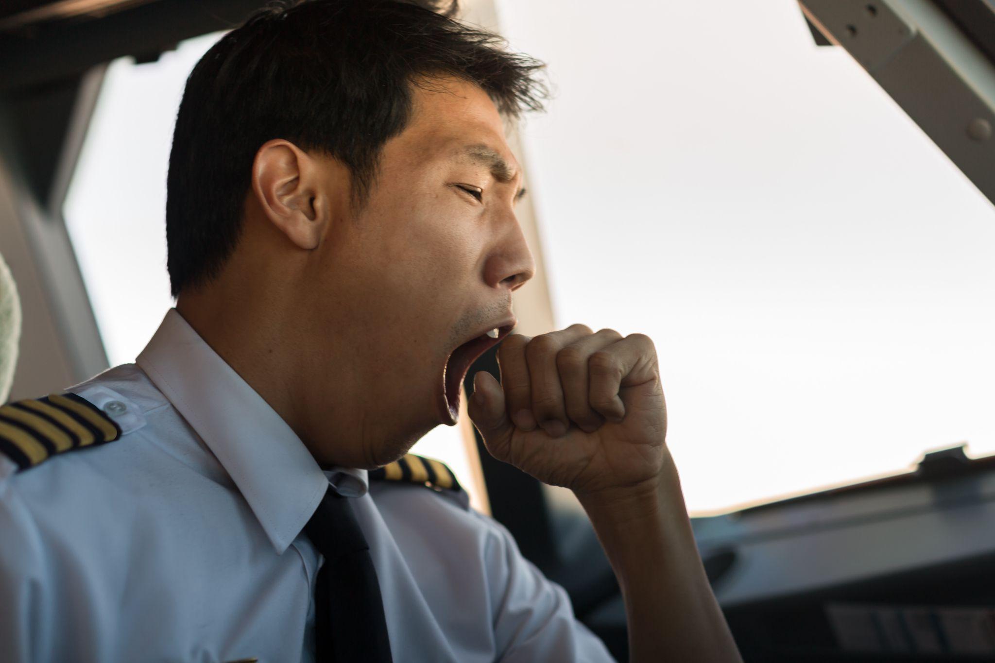 Tired pilot yawning at work