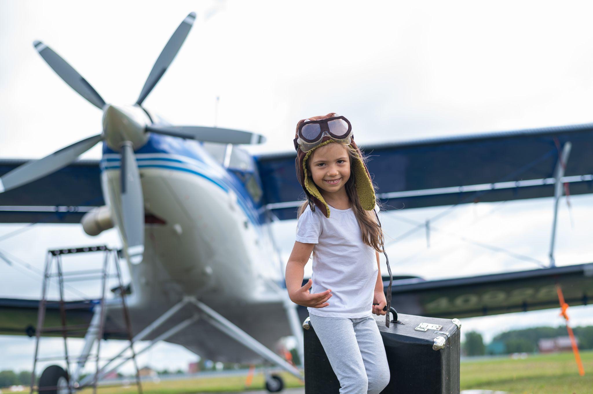 A cute little girl playing on the field by private jet dreaming of becoming a pilot