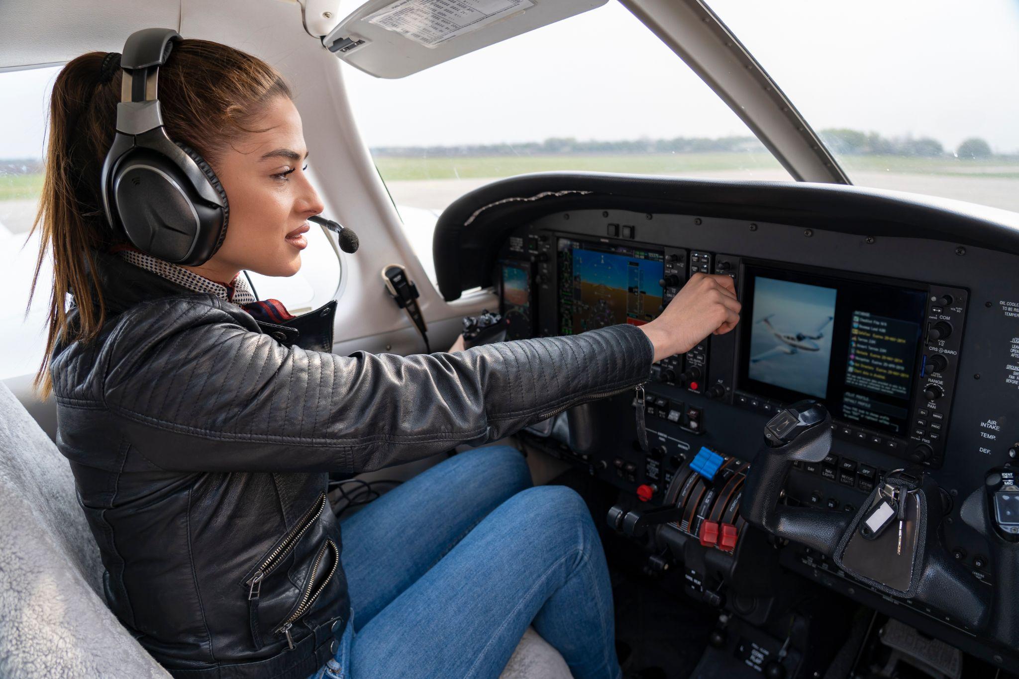 Portrait of attractive young woman pilot with headset in the cockpit