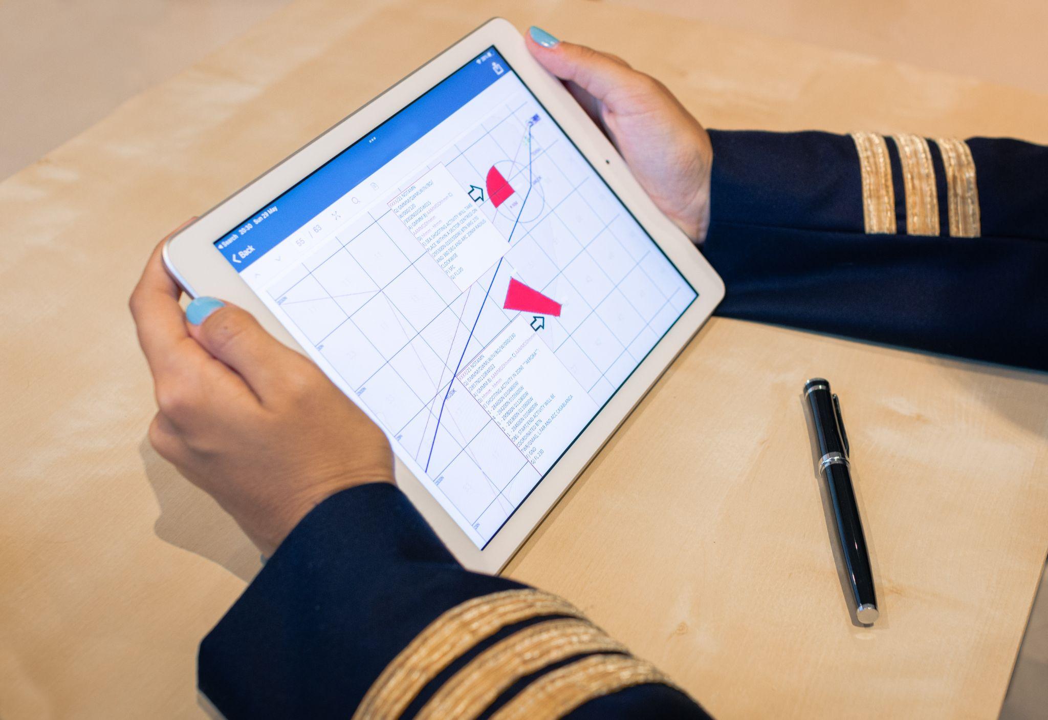 female pilot preparing flight documentation on a tablet.