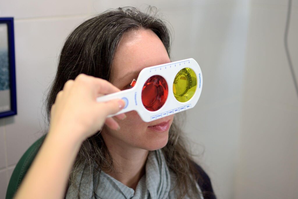 Female optometrist or ophthalmologist optician performs a color blindness test on woman