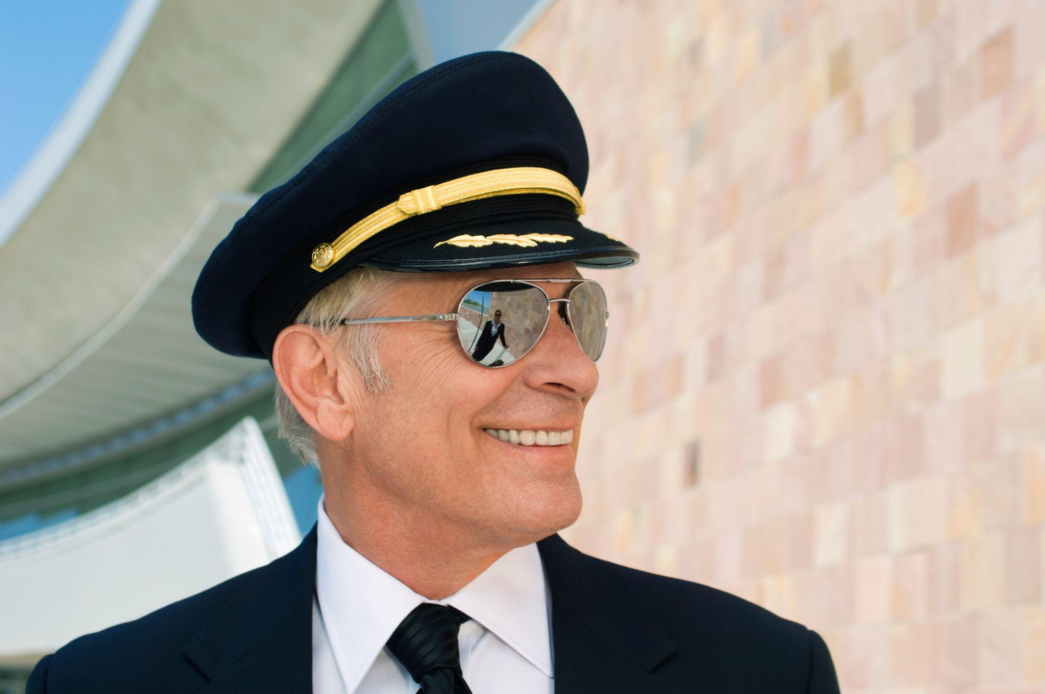 Close up of a happy senior airline pilot outside of airport.