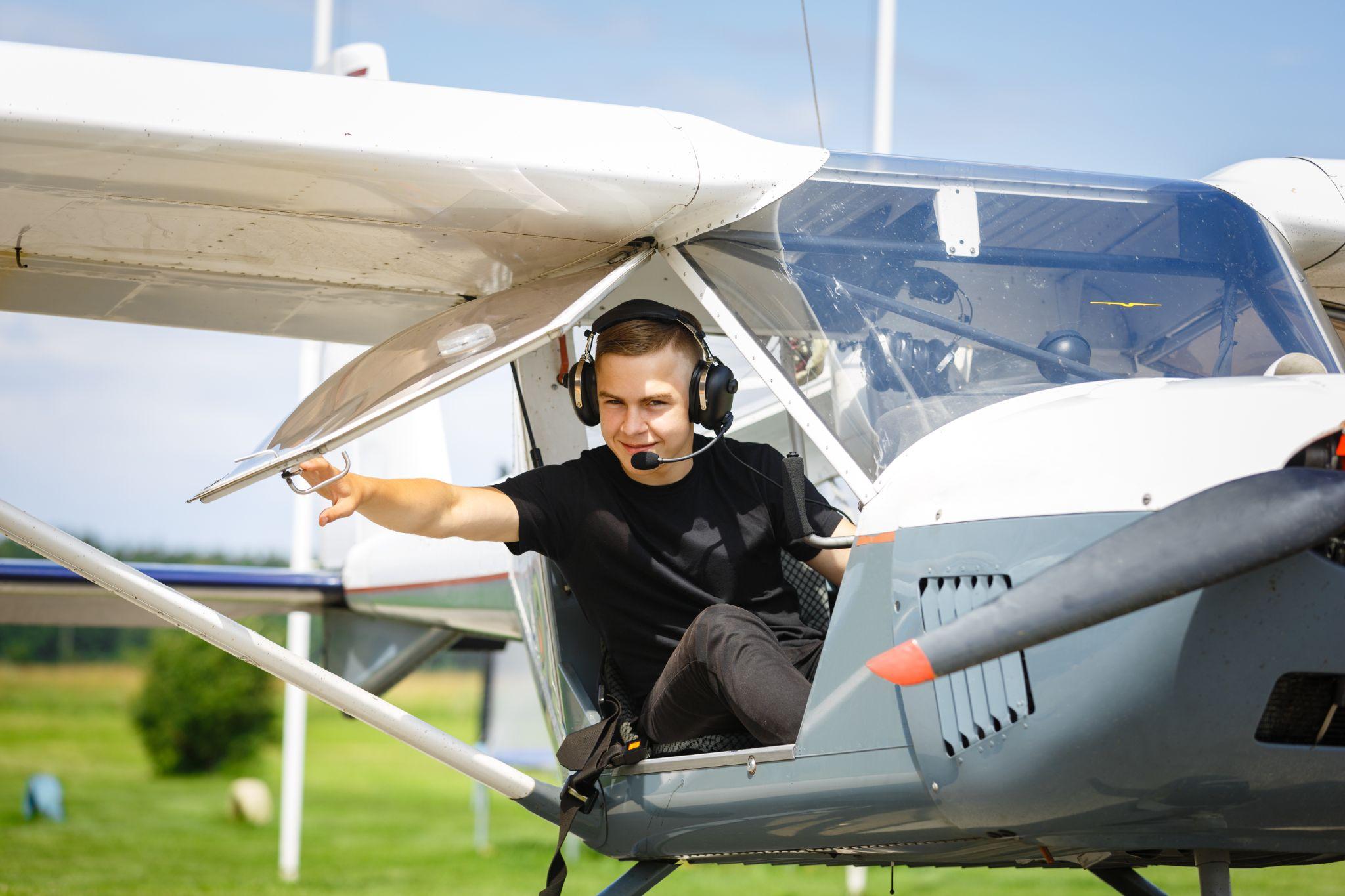 Young pilot closing door in small private plane.