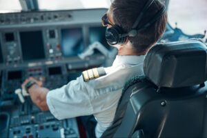 Male pilot flying passenger plane on sunny day.