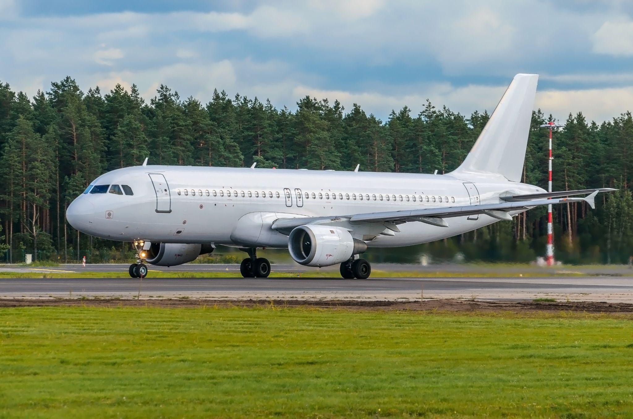 White Airbus A320 on tarmac with grass.