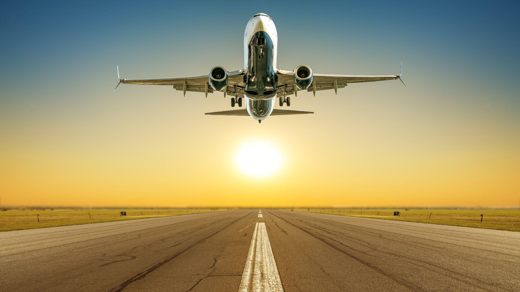 commercial airplane taking off against a sunset.