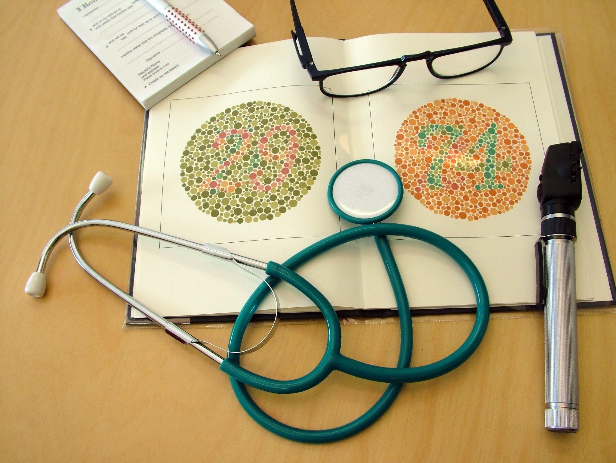 Medical equipment on wooden table with color blindness test booklet
