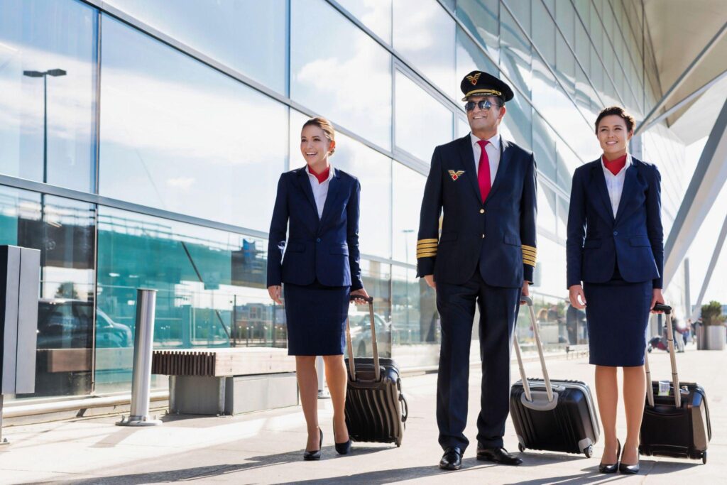 Mature pilot with young beautiful flight attendants walking in airport.
