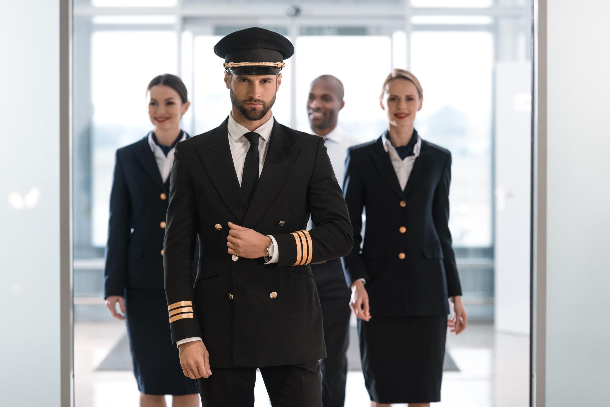 Pilot at airport with his team looking at camera.