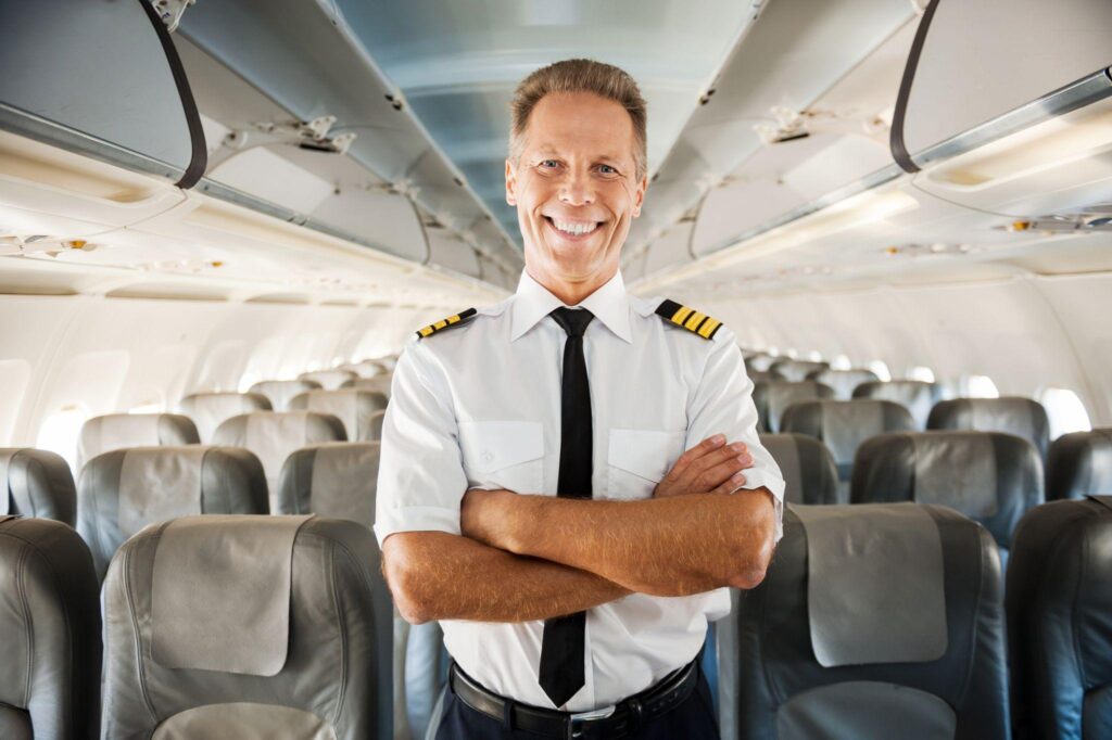 A international pilot stands confidently inside a passenger aircraft.