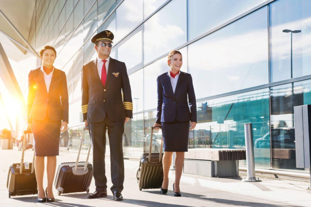 An international pilot walks with flight attendants outside the airport terminal.
