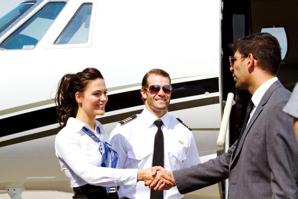 Stewardess and pilot greeting passenger.