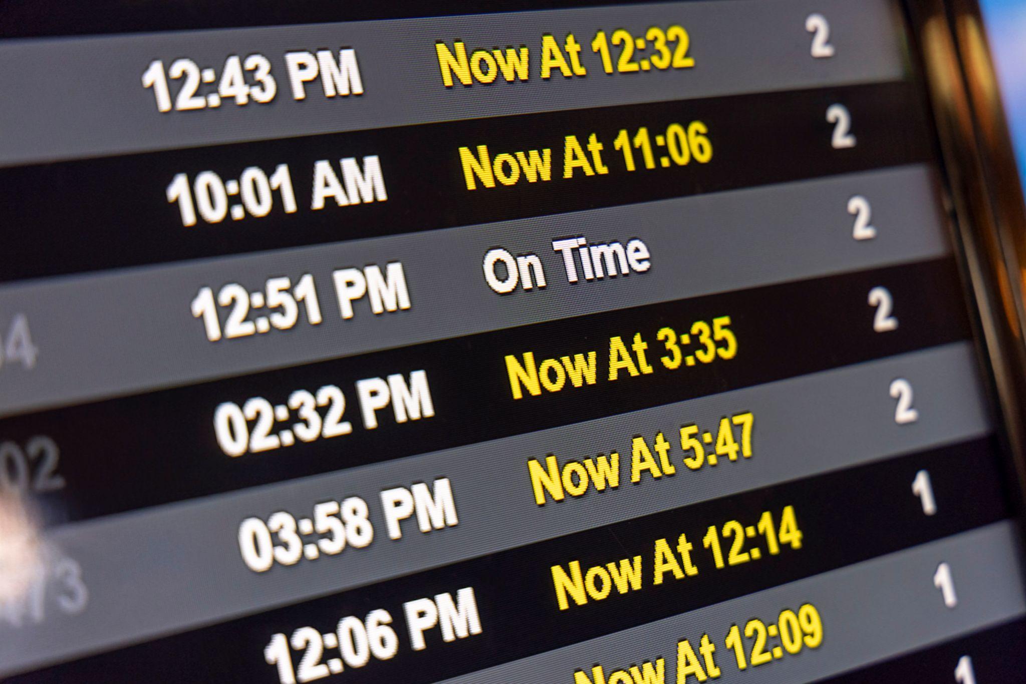 An airline schedule digital display showing delayed and cancelled flights.