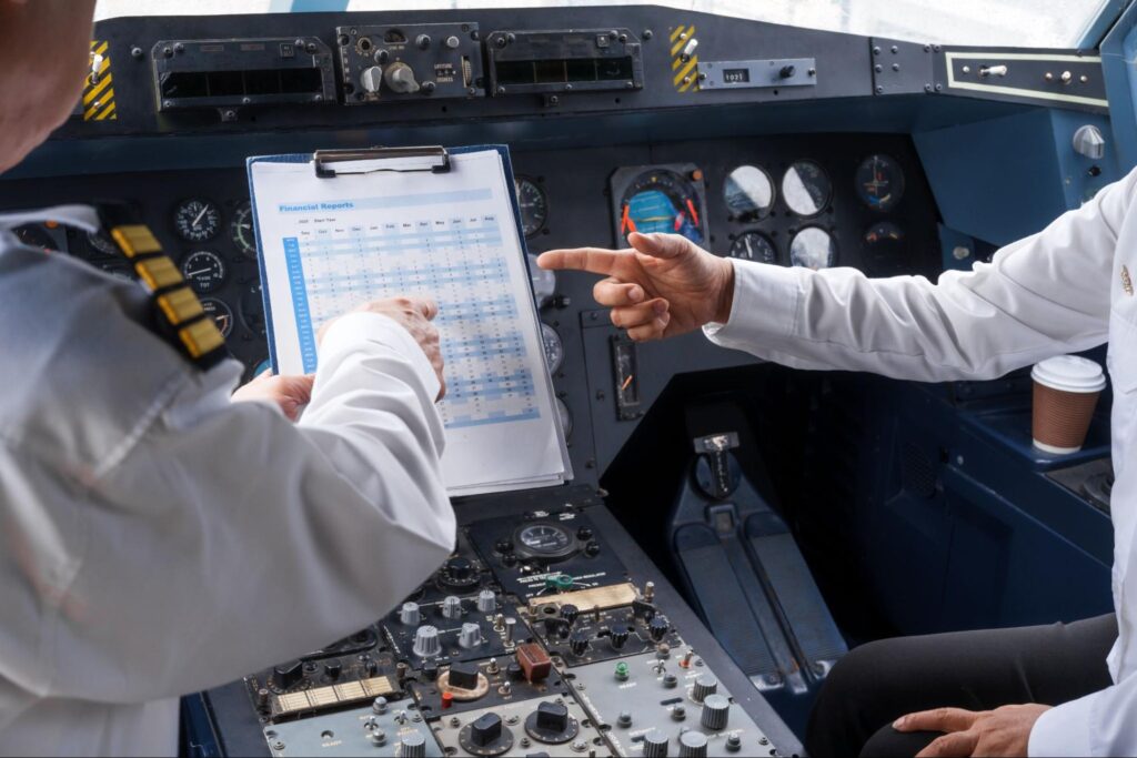 Mature male and female pilots meet inside an airplane, holding hands.
